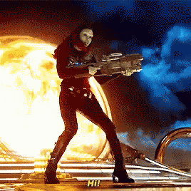a woman in a superhero costume is holding a gun in front of a large explosion .