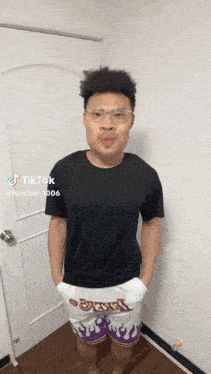a man wearing a black shirt and white shorts is standing in front of a door .