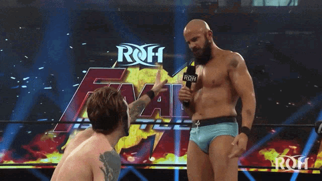 a wrestler holds a microphone in front of a sign that says final battle