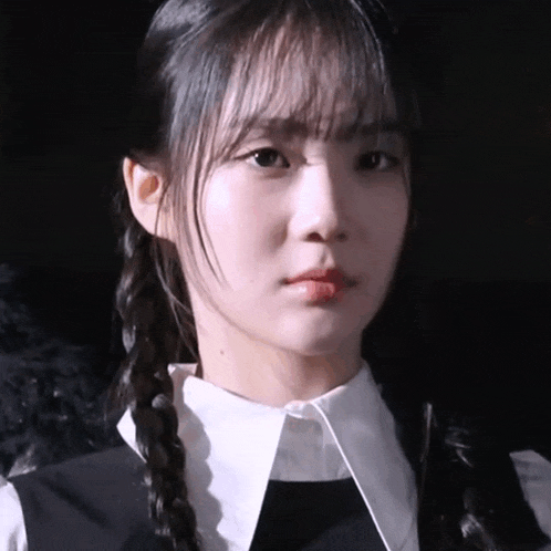 a close up of a woman 's face with braids and a white collar