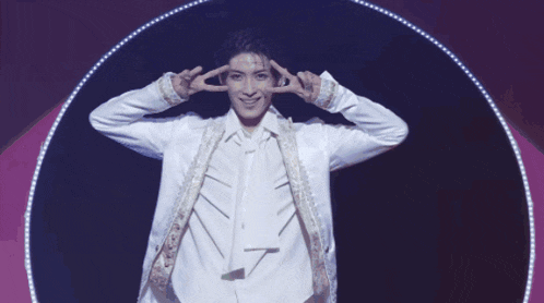 a man in a white jacket and tie is giving the peace sign