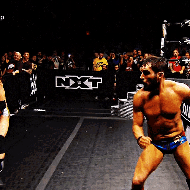 two wrestlers are standing in front of a banner that says nxt