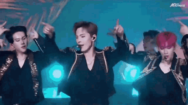 a group of young men are dancing on a stage in front of a blue background .