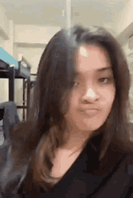 a young girl with long hair is making a funny face .