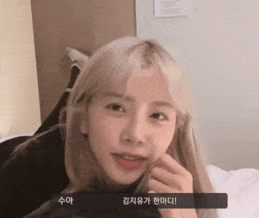 a girl with blonde hair is laying on a bed with korean writing on the bottom right