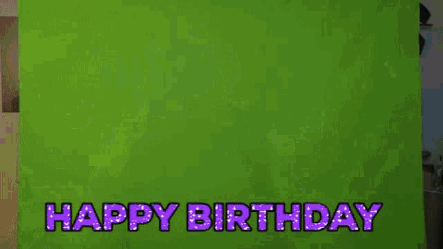 a woman is jumping in the air in front of a green screen with the words happy birthday written in purple letters .