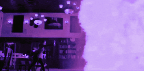 a blurry picture of a room with purple smoke coming out of the corner