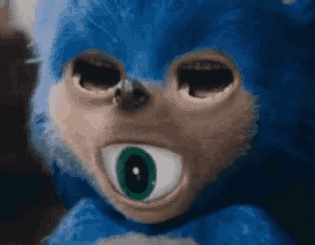 a close up of a blue stuffed animal with a green eye