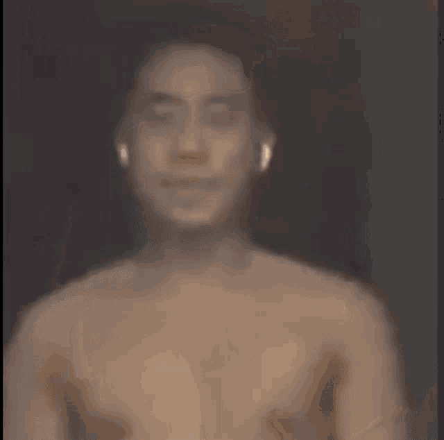 a shirtless man wearing ear buds is standing in front of a dark background .