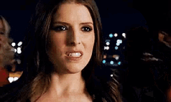 a close up of a woman making a funny face while another woman looks on .