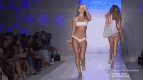 two women in bikinis walk down a runway at a frankie 's bikinis fashion show