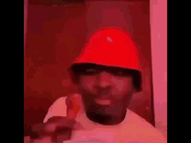 a man wearing a red bucket hat is pointing at the camera .