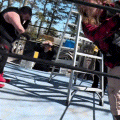 a man and a woman are wrestling in a ring with a ladder in the foreground