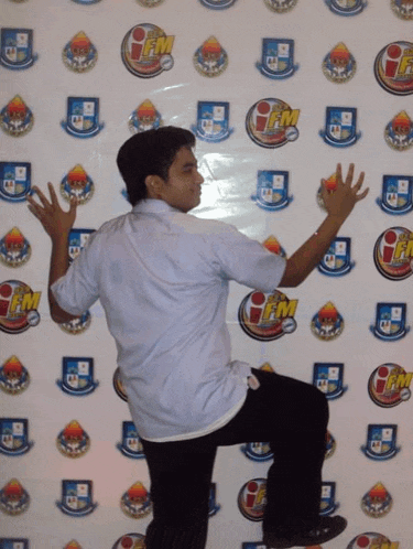 a man stands in front of a wall that has logos for fm on it