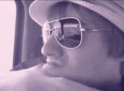 a woman wearing a hat and sunglasses looks out a window