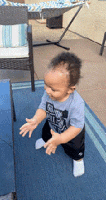 a baby wearing a shirt that says ' i love you ' on it is standing on a blue rug