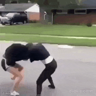 two girls are fighting on the side of a road .