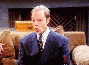 a man in a suit is sitting on a couch with his mouth open