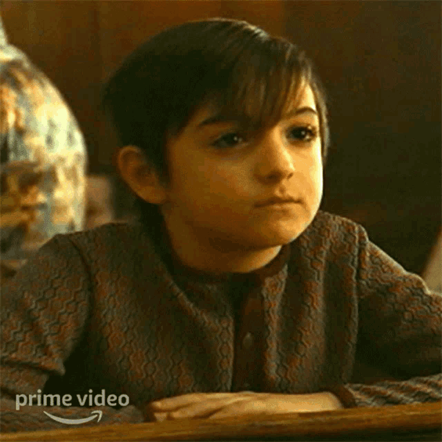 a young boy is sitting at a desk with his eyes closed and the words got it written on the screen .