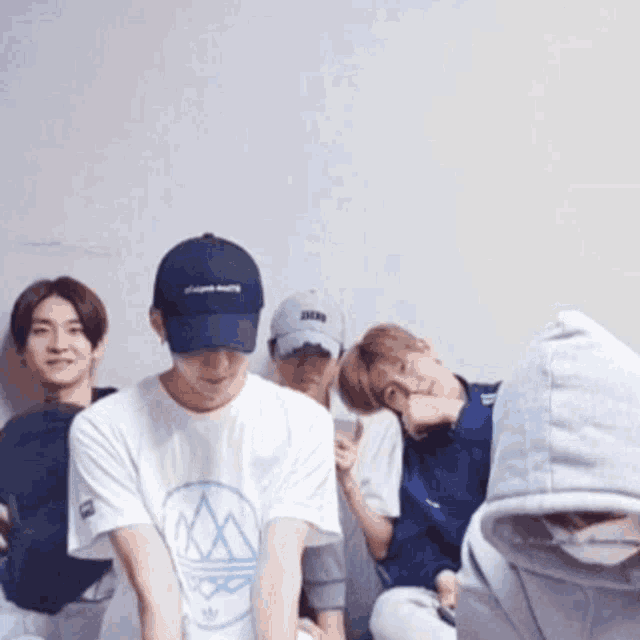 a group of young men wearing hats and hoodies are posing for a picture