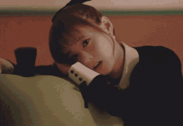 a girl leaning on a green apple with her hand on her face