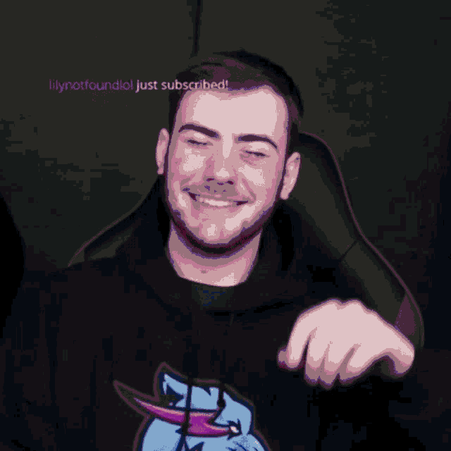a young man with a beard is sitting in a chair and smiling .