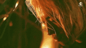 a close up of a person 's face with a fire behind them .