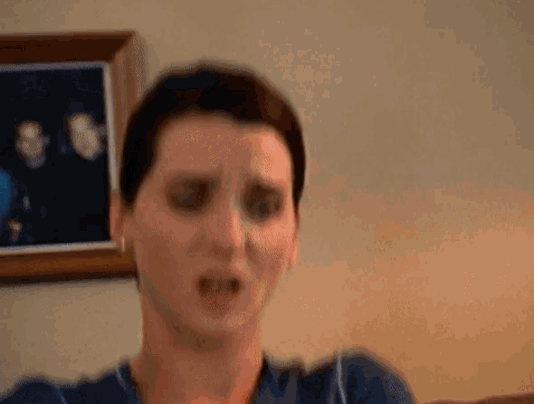 a woman is making a funny face in front of a framed picture of her family .