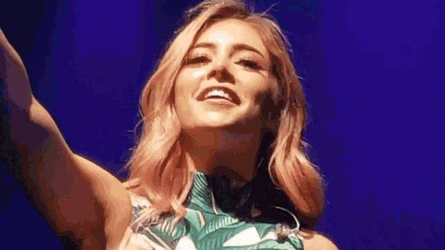 a woman with pink hair is smiling with her arms outstretched