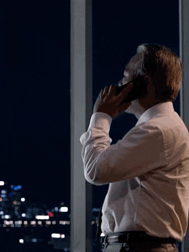 a man in a white shirt is talking on his cell phone