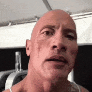 a close up of a man 's face with a bald head and a tattoo on his chest .