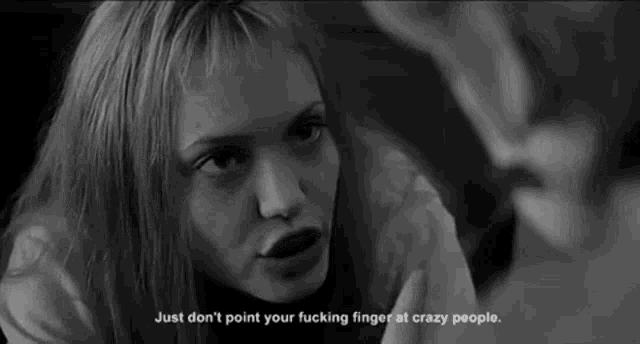 a black and white photo of a woman talking to a man with the words just don 't point your fucking finger at crazy people
