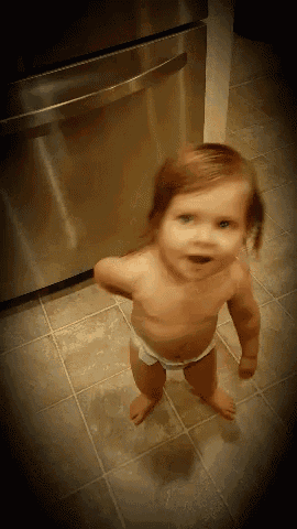 a baby wearing a diaper is standing on a tiled floor