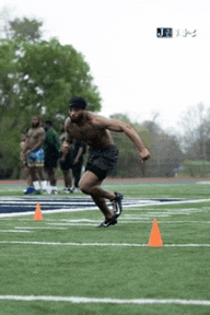 a man without a shirt is running on a field with cones