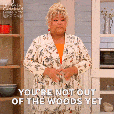 a woman in a floral suit is standing in a kitchen and says you 're not out of the woods yet
