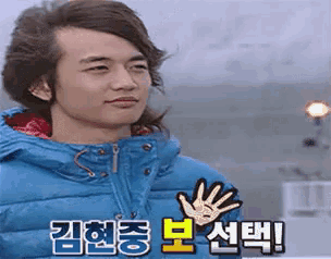 a man in a blue jacket is waving his hand in korean