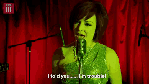 a woman singing into a microphone with the words i told you i 'm trouble below her