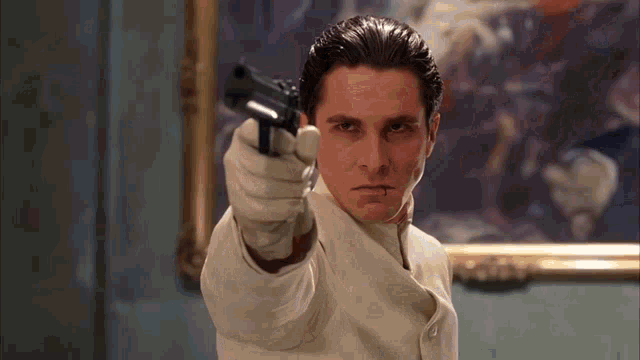 a man in a white suit is pointing a gun at something