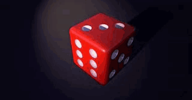 a red dice with white dots on a black surface .