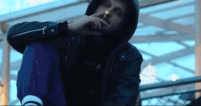 a man in a hoodie smoking a cigarette