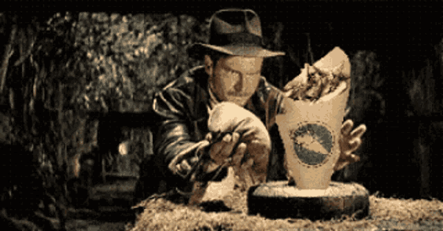 a man in a hat is holding a cup that says ' a ' on it