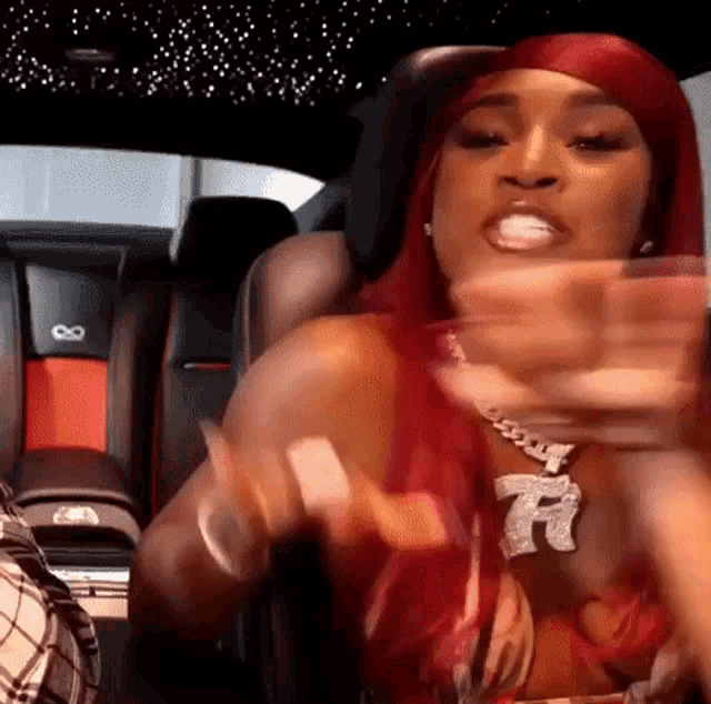a woman with red hair is sitting in the back seat of a car and making a funny face .