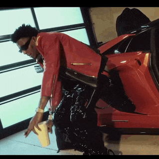a man in a red leather jacket is kneeling down next to a red car