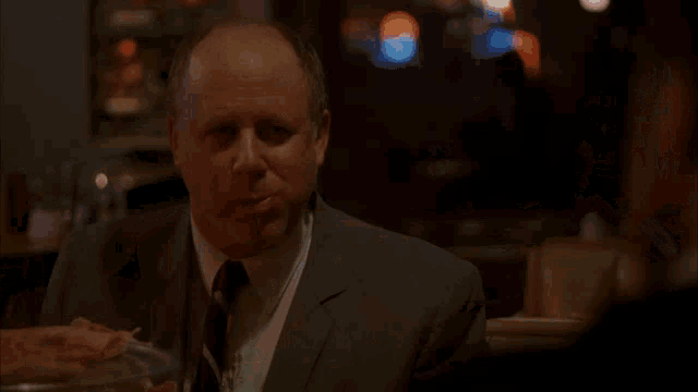 a man sits at a table in a diner with a neon sign that says bbq chicken