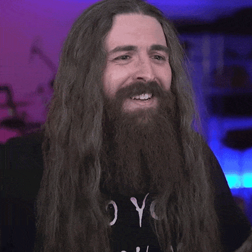 a man with long hair and a beard is clapping his hands together