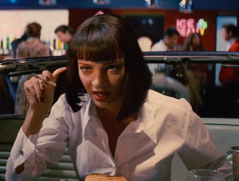 a woman is smoking a cigarette while sitting in a diner .