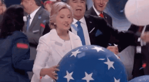 hillary clinton is holding a blue balloon with white stars on it .