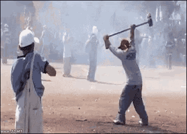 a man is swinging a hammer at another man in a crowd .