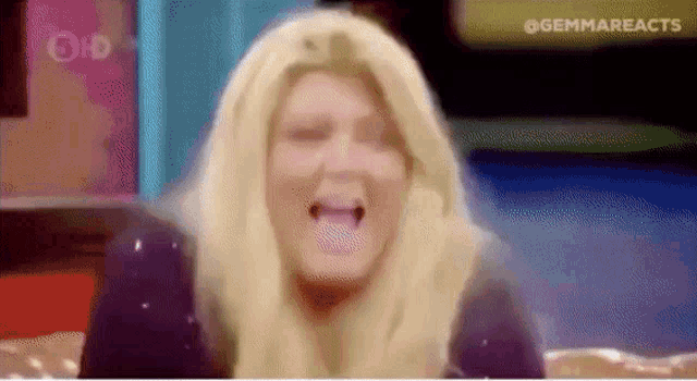 a woman with blonde hair is making a funny face while sitting on a bed .