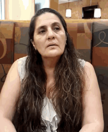 a woman with long hair is sitting in a booth and looking at the camera